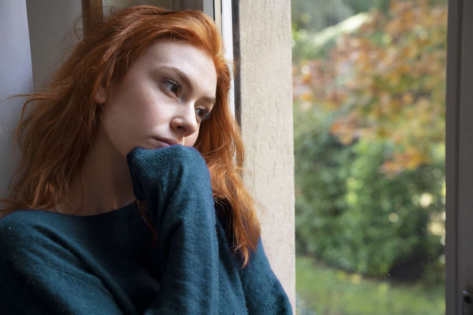 a sad woman looks out the window