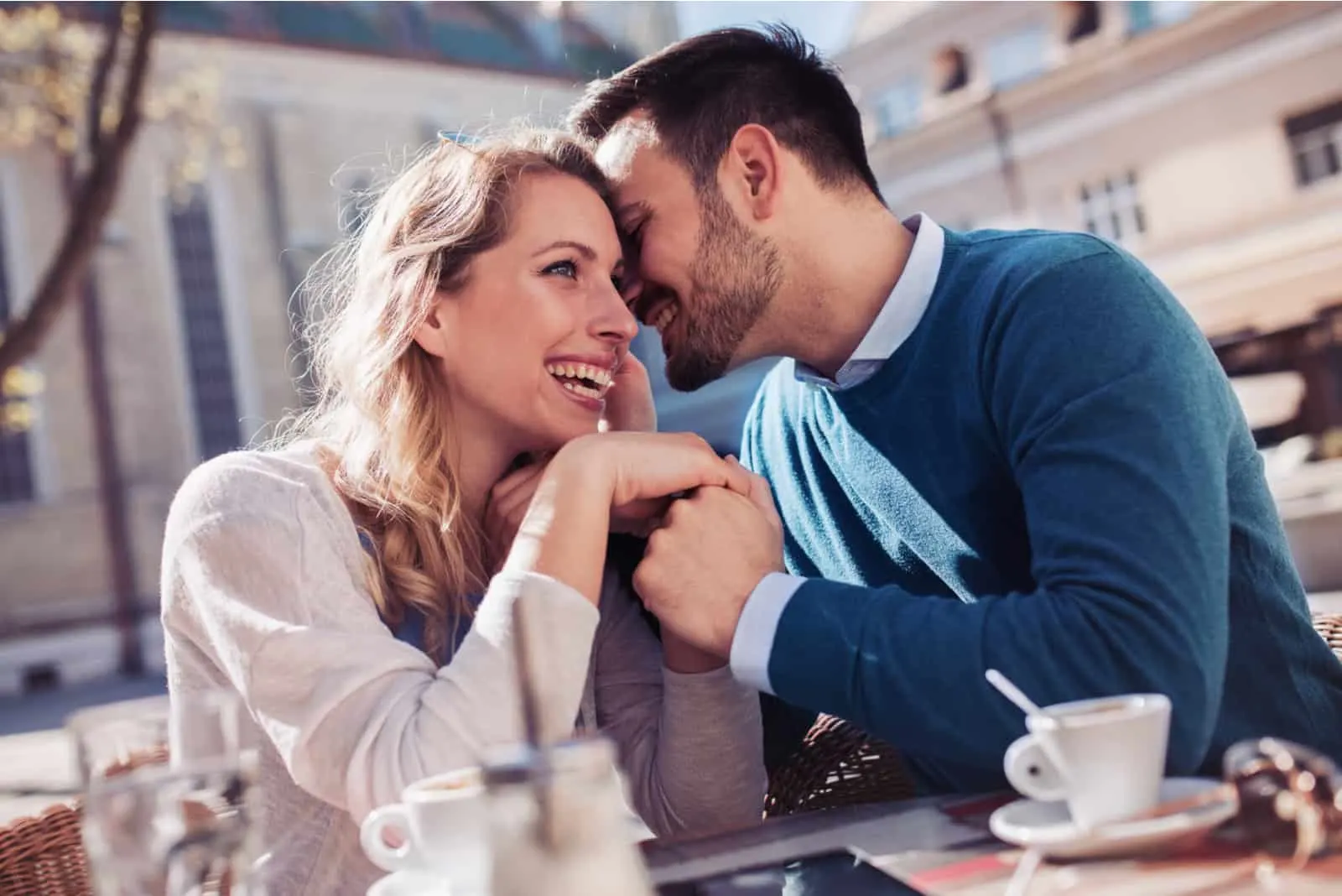 a smiling loving couple sitting outdoors holding hands and talking