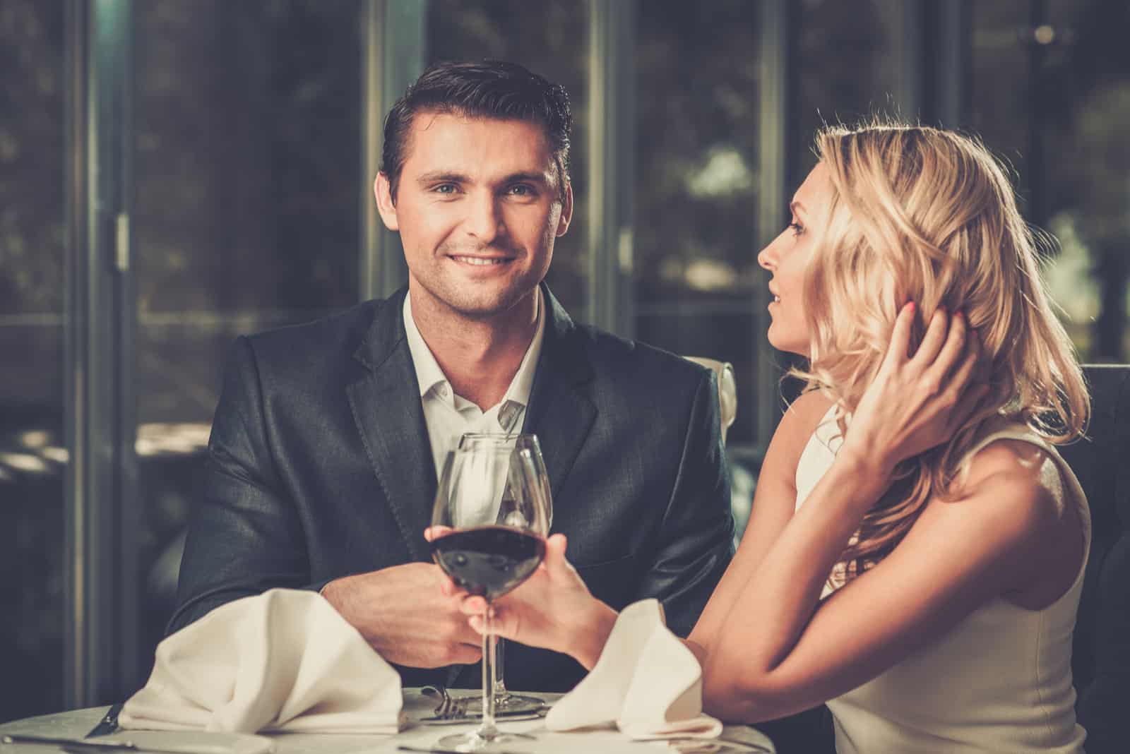 a smiling man and woman drinking wine