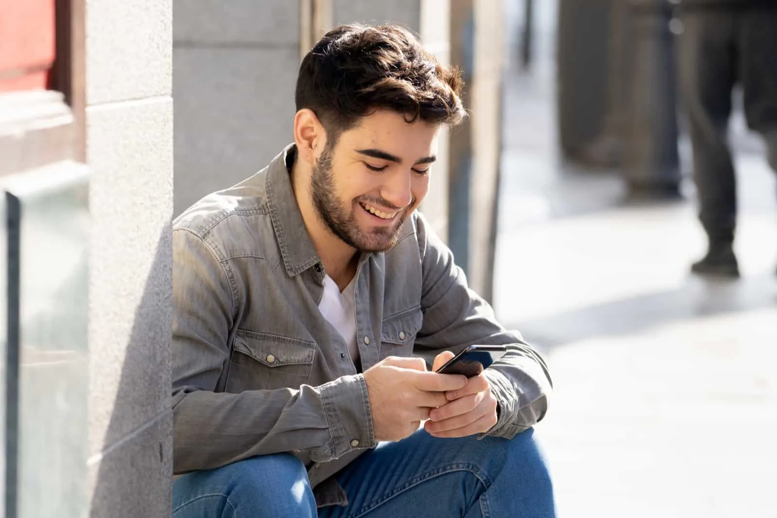 a smiling man sits on the stairs and buttons on the phone