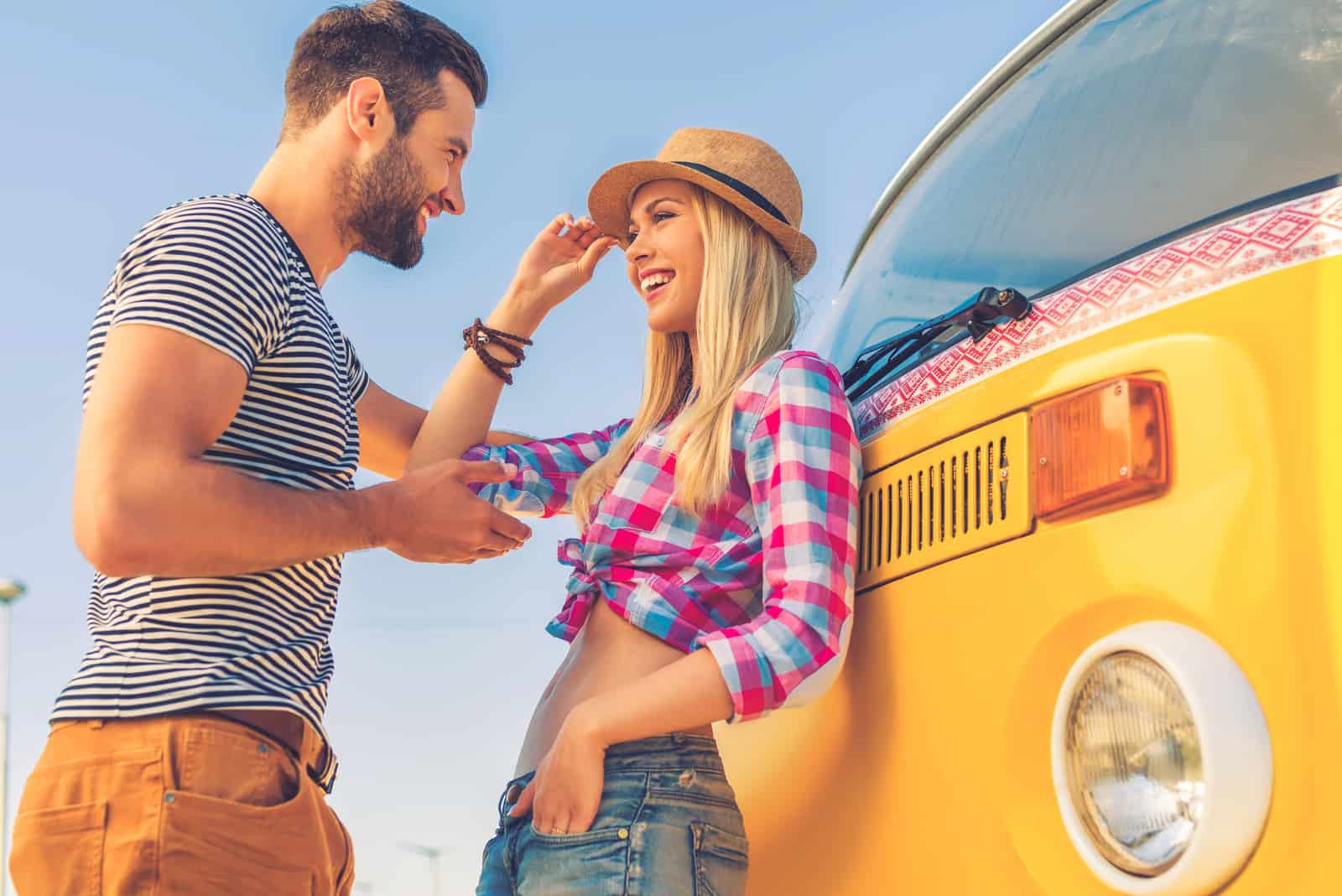 a smiling woman with a hat on her head talking to a man