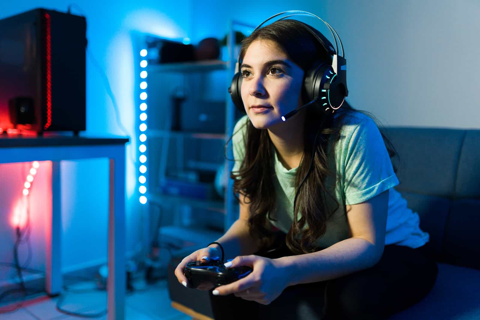a woman sitting on a couch with headphones on and playing video games