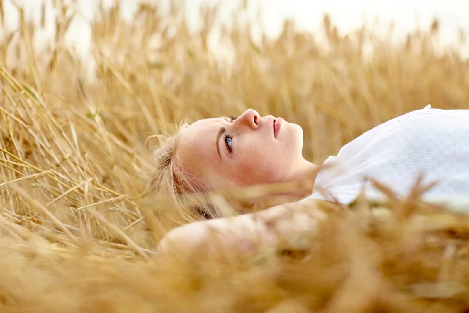 a woman with long blonde hair lies in the grass