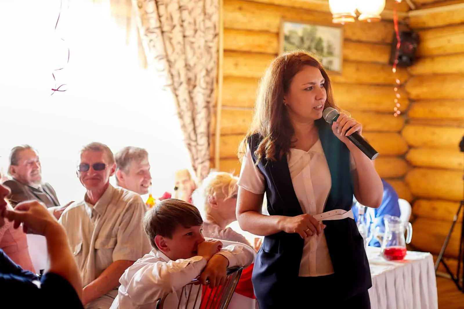 a woman with long brown hair gives a speech at a wedding
