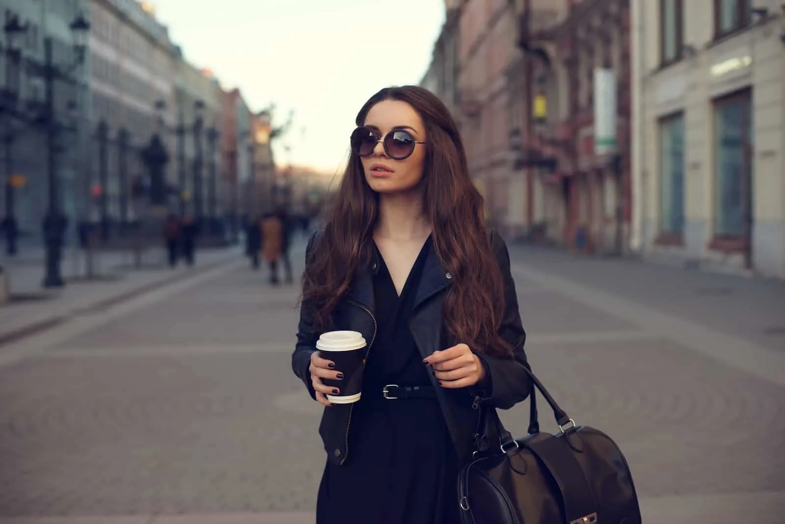 a woman with long brown hair walks down the street