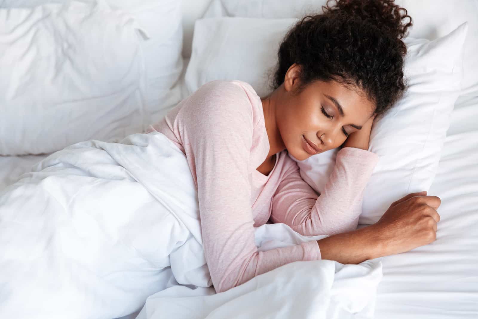 uma mulher de cabelo amarrado dorme na cama