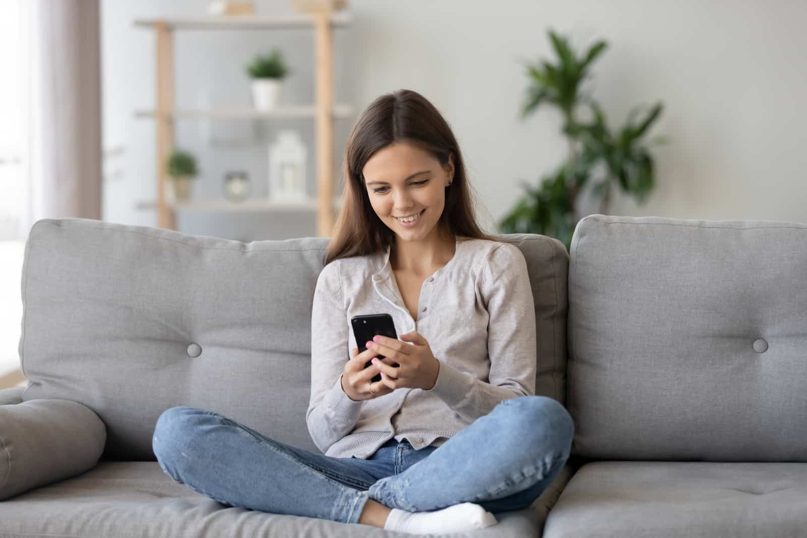 mujer sentada en su sofá enviando mensajes de texto