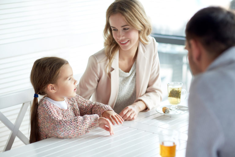 a man and a woman are sitting at a table with a child