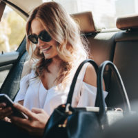 woman in car holding her phone and thinking about snapchat caption