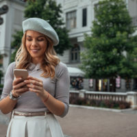beautiful woman with a hat on her head button on the phone