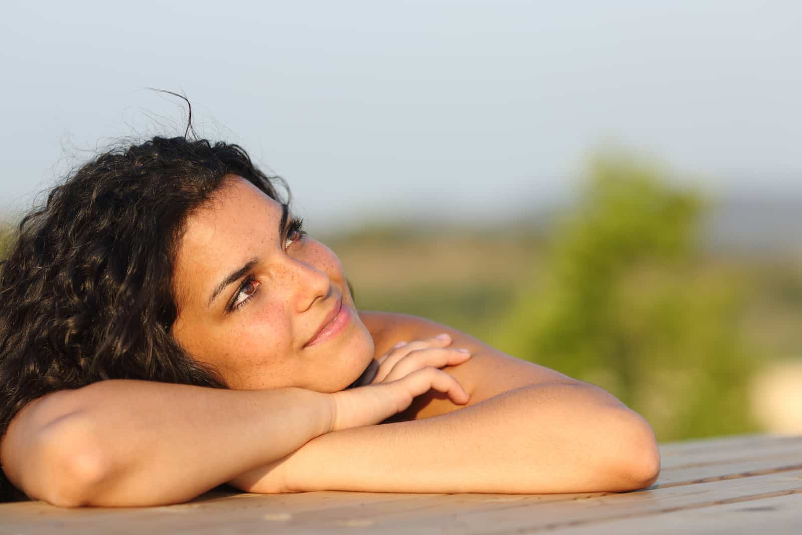 Candid girl dreaming and thinking leaning on a table outdoors