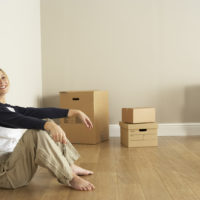 woman sitting on floor with cardboard boxes behind her