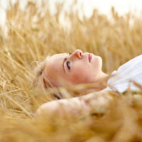 uma mulher imaginária de cabelo loiro deita-se num campo e olha para o céu