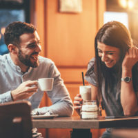 una coppia sorridente e innamorata seduta al tavolo di un caffè