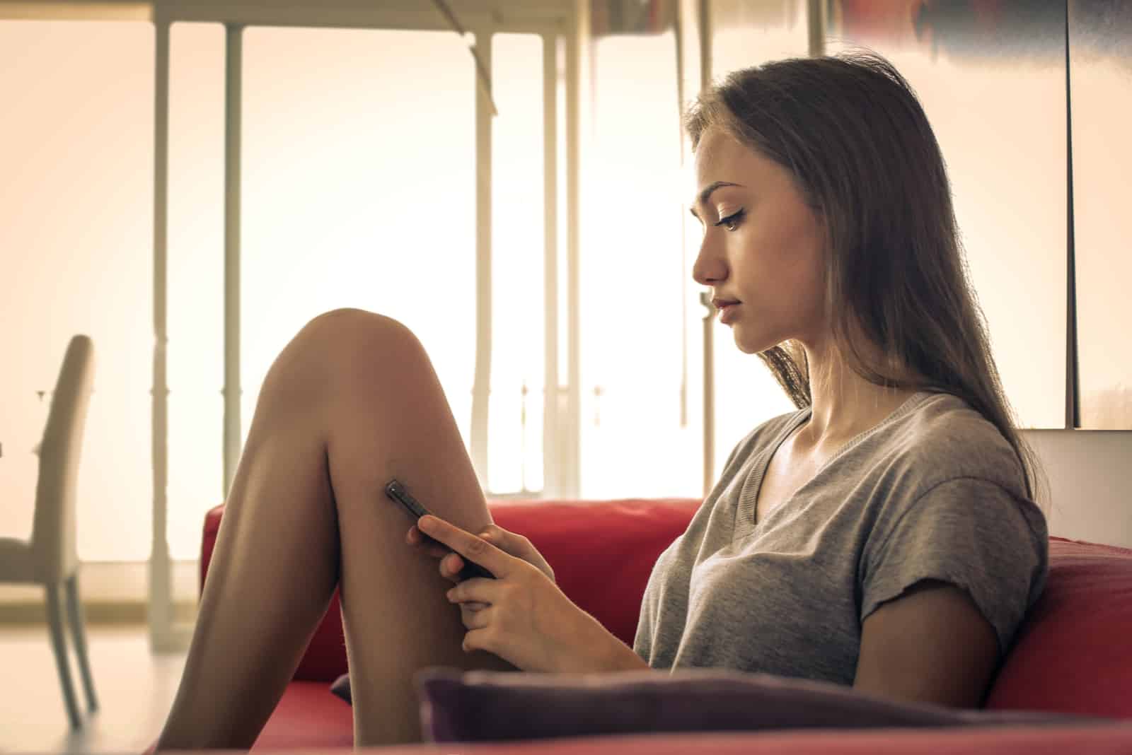 an imaginary woman with long brown hair sits on the couch and holds a cell phone in her hand
