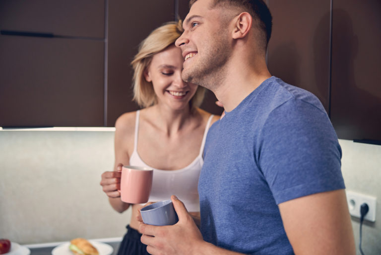 a smiling loving couple standing in the kitchen