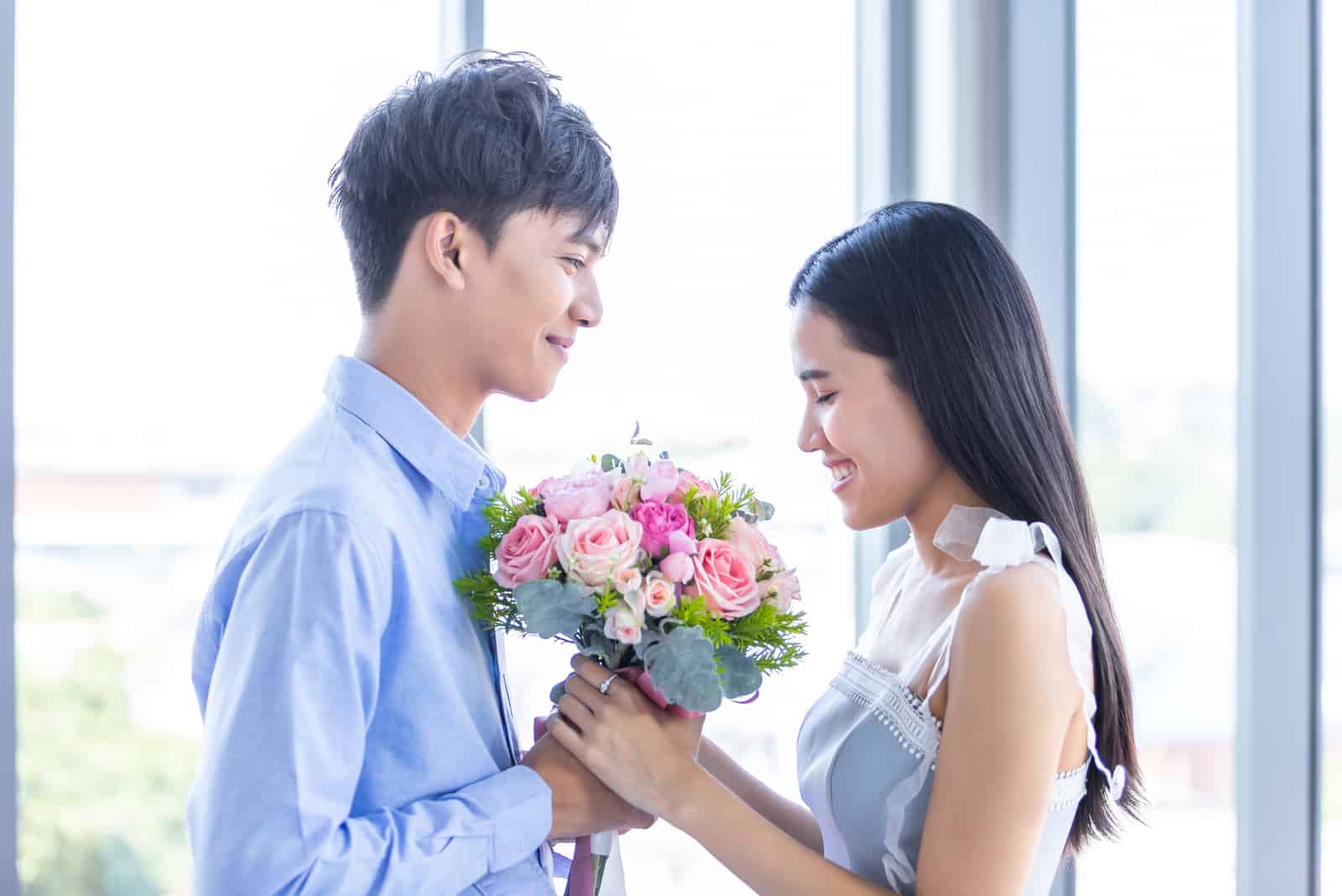 a man gives a gift of a bouquet of roses to a woman