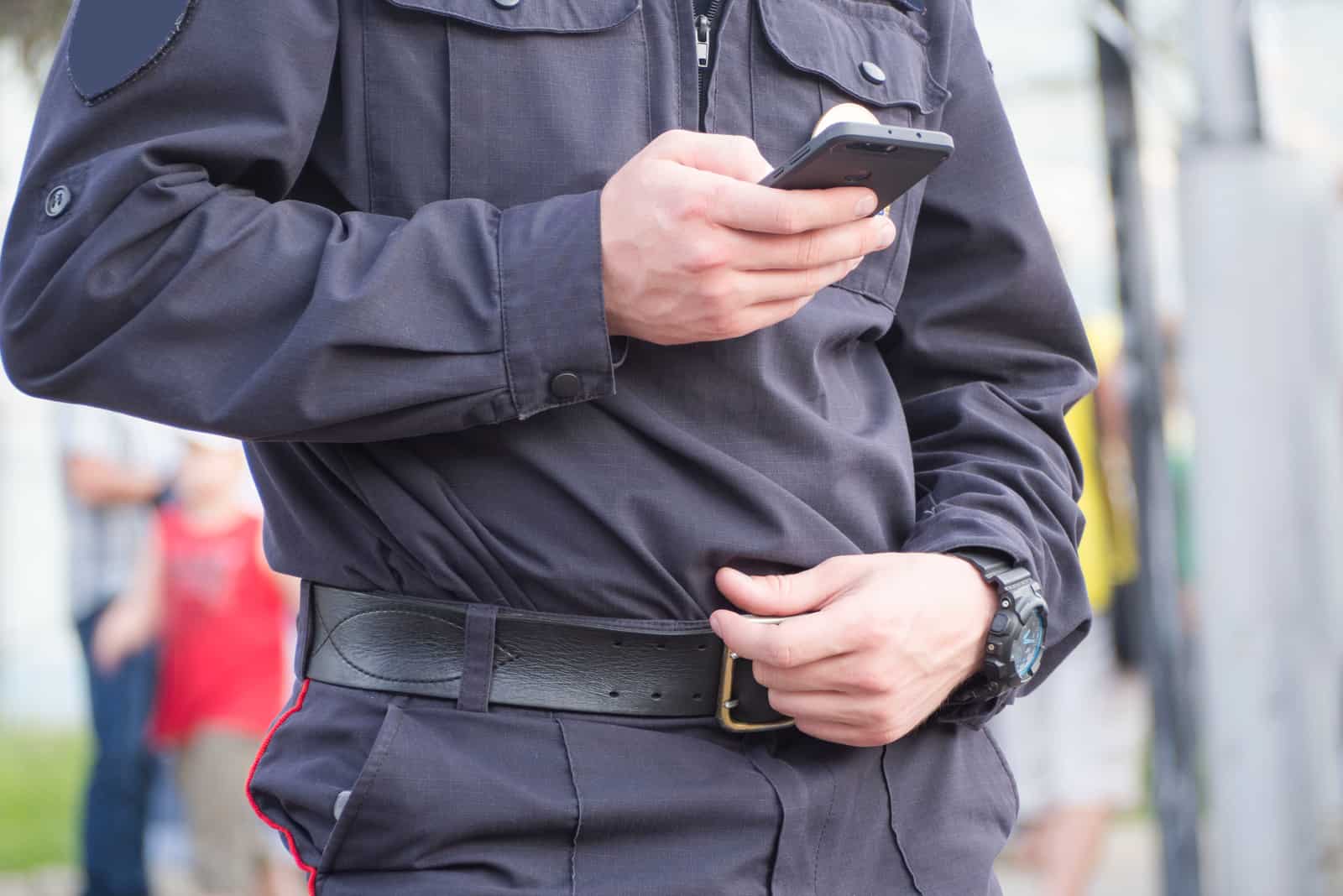 a man in the police department is standing and holding a phone in his hand