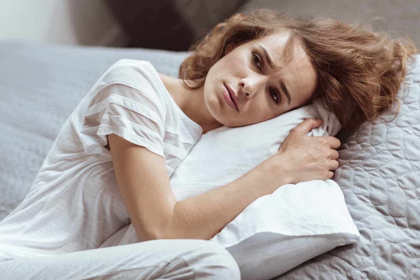 a sad woman lying on a pillow