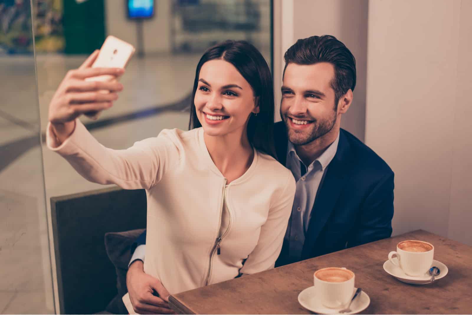 una coppia sorridente e innamorata seduta a un tavolo a scattare fotografie