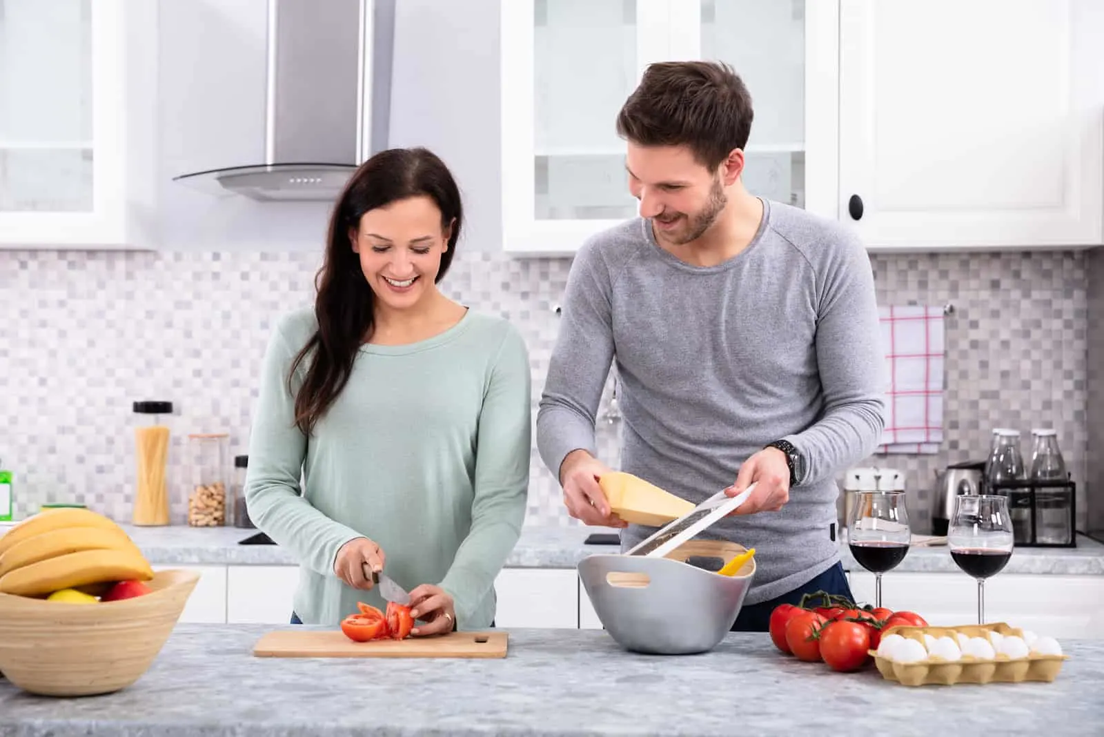 a smiling man helps a woman in the kitchen