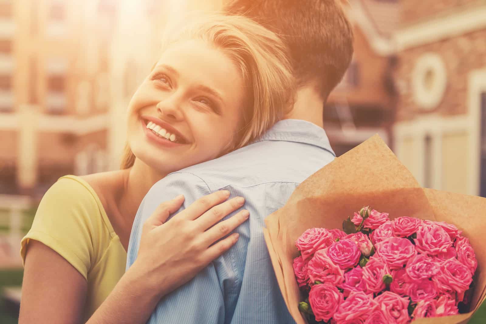 a smiling woman in her arms holding a bouquet of roses
