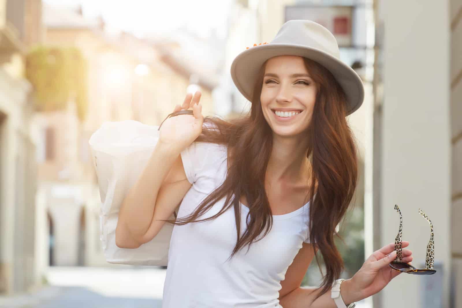 una mujer sonriente con un sombrero en la cabeza se para en la calle