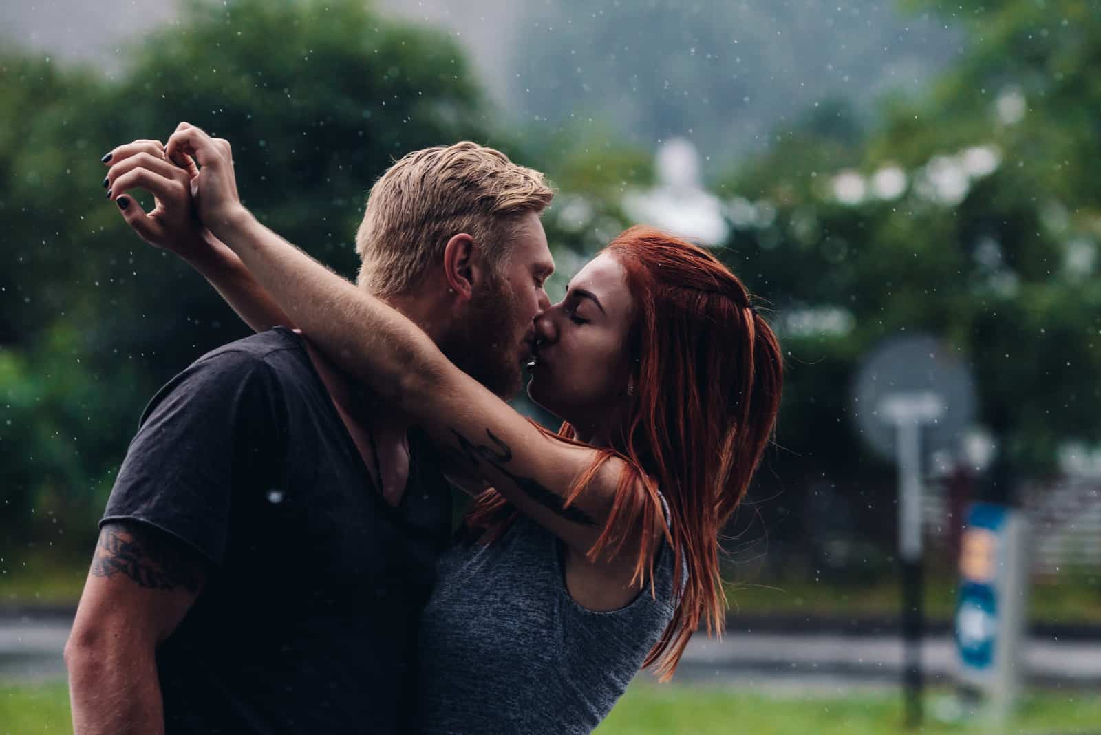 bella coppia che si bacia all'aperto sotto la pioggia