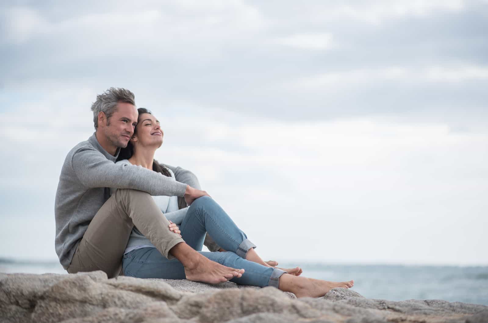 couple sitting on rock by sea