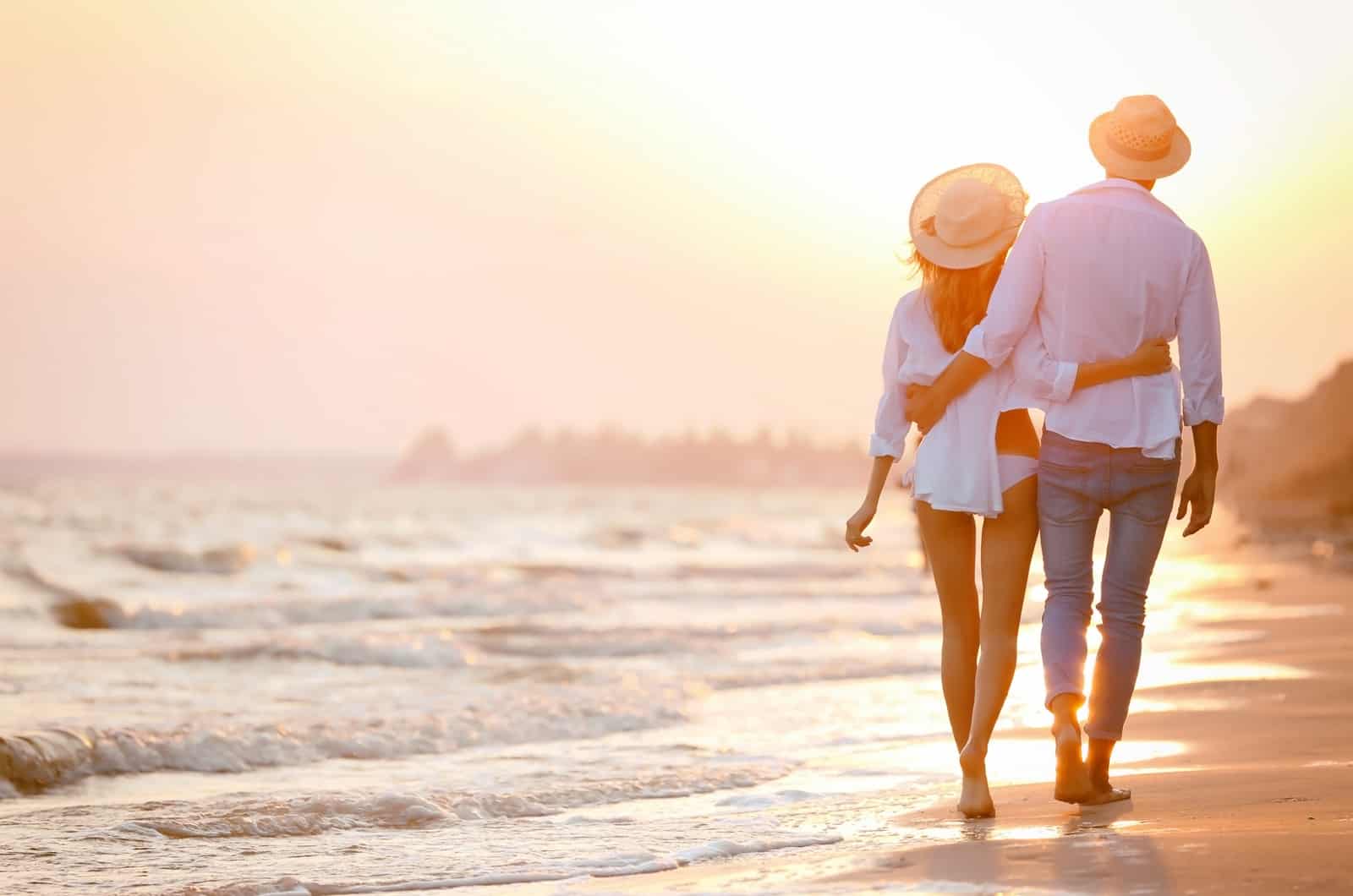 pareja caminando por la orilla del mar al atardecer