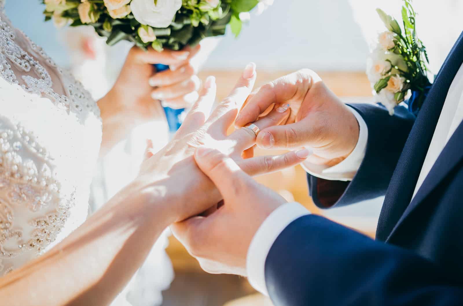 groom putting wedding ring on bride