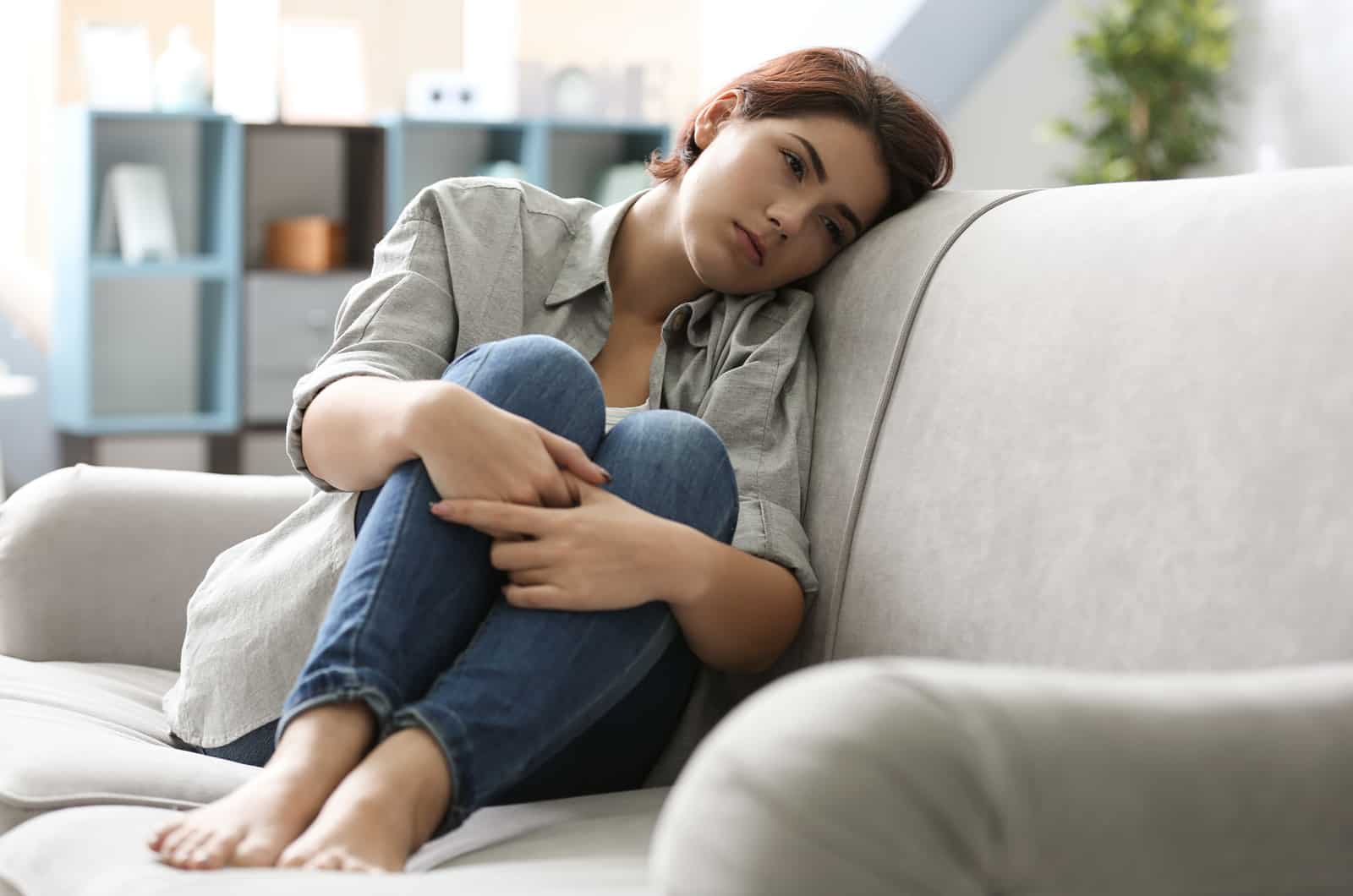 mulher triste sentada no sofá