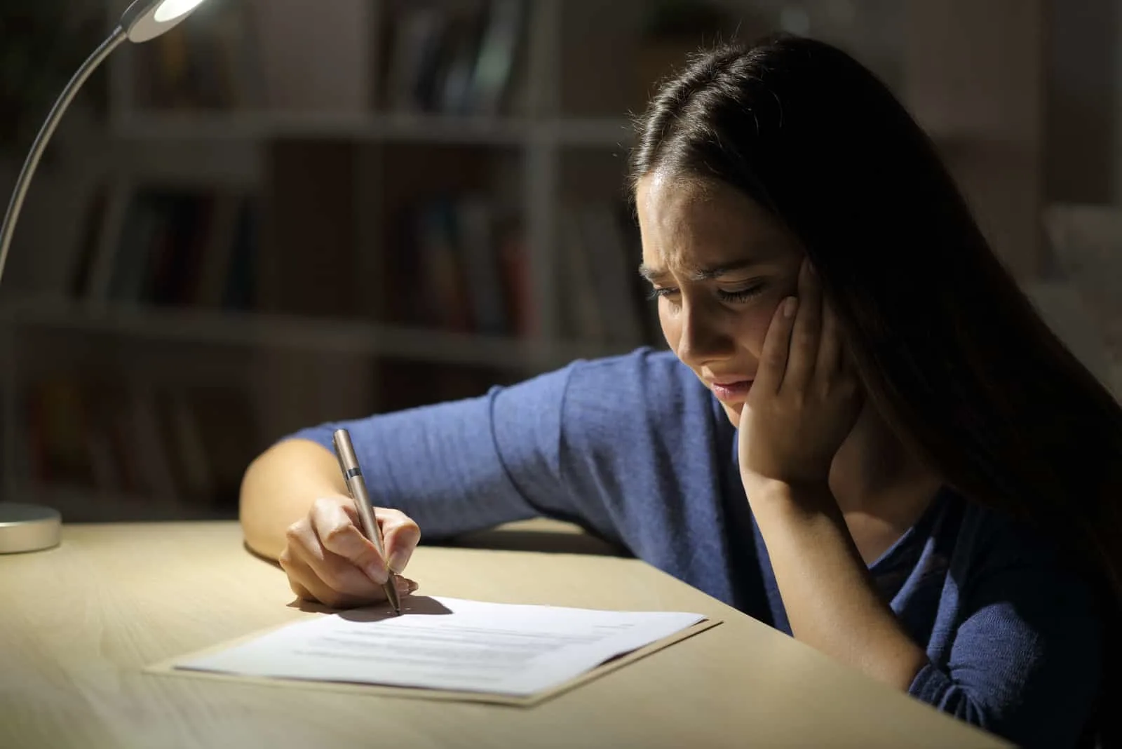 sad woman writing a letter in dark room