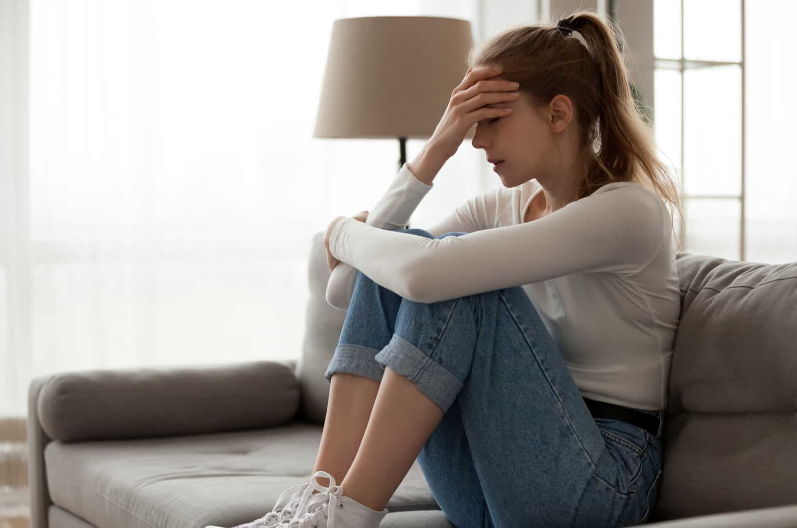 sad young woman sitting at couch