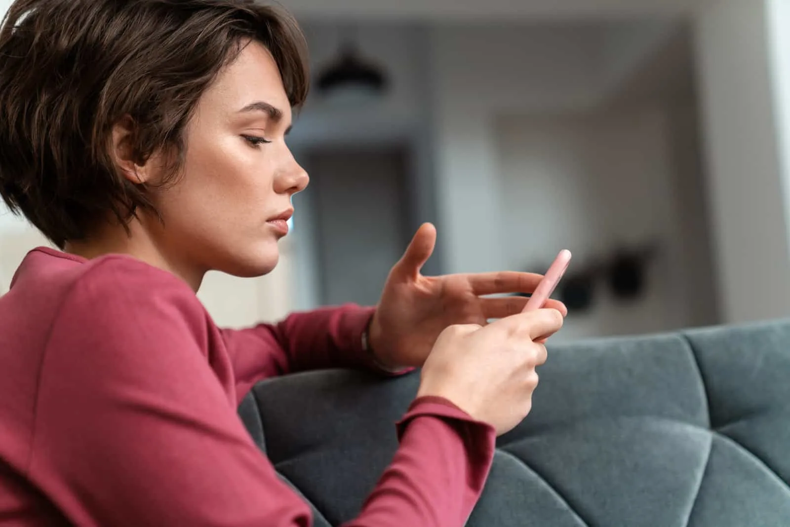 serious woman looking at mobile phone on the couch