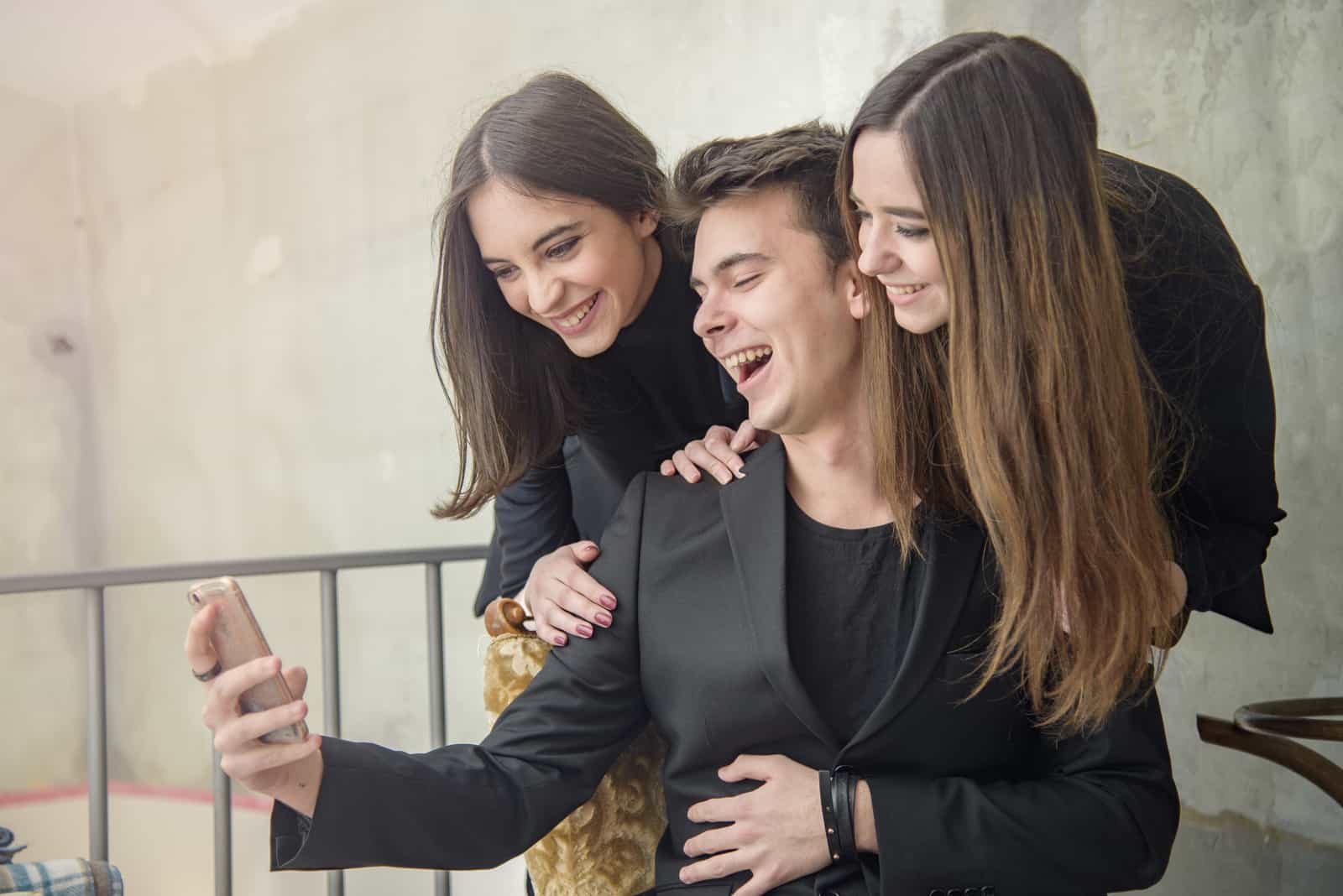 smiling man taking picture with his friends for snapchat