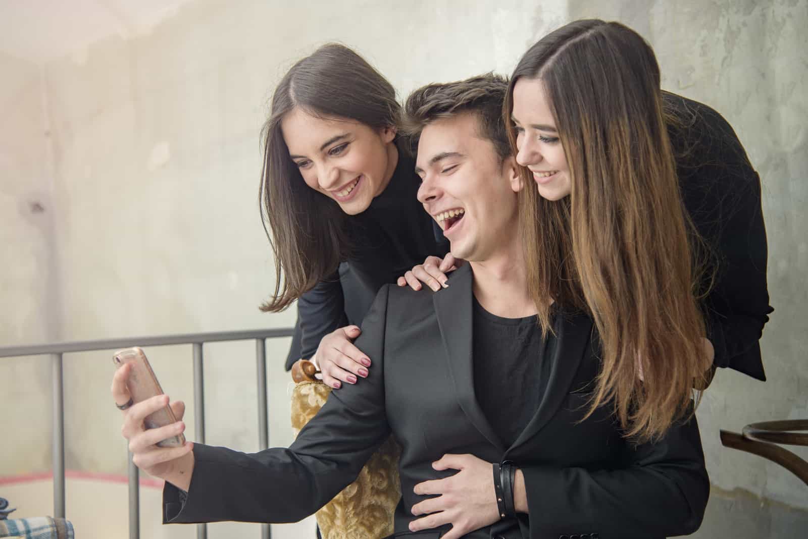 hombre sonriente haciendose una foto con sus amigos para snapchat