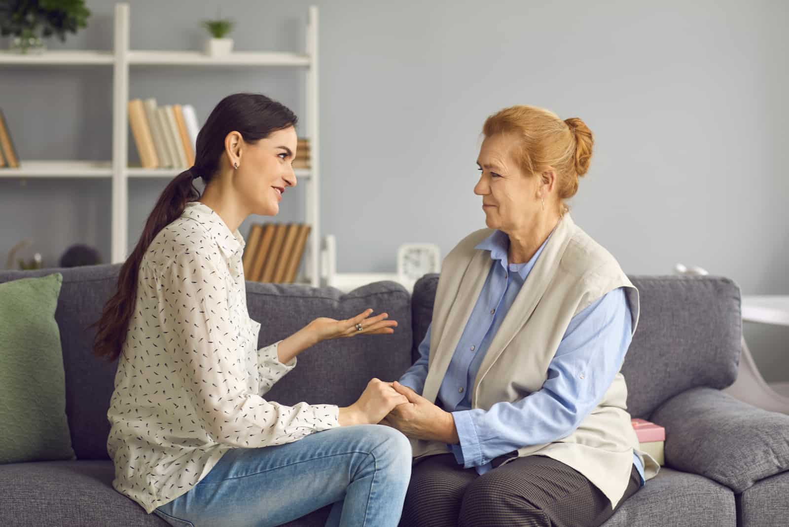 the woman sits with her mother-in-law on the couch and they talk