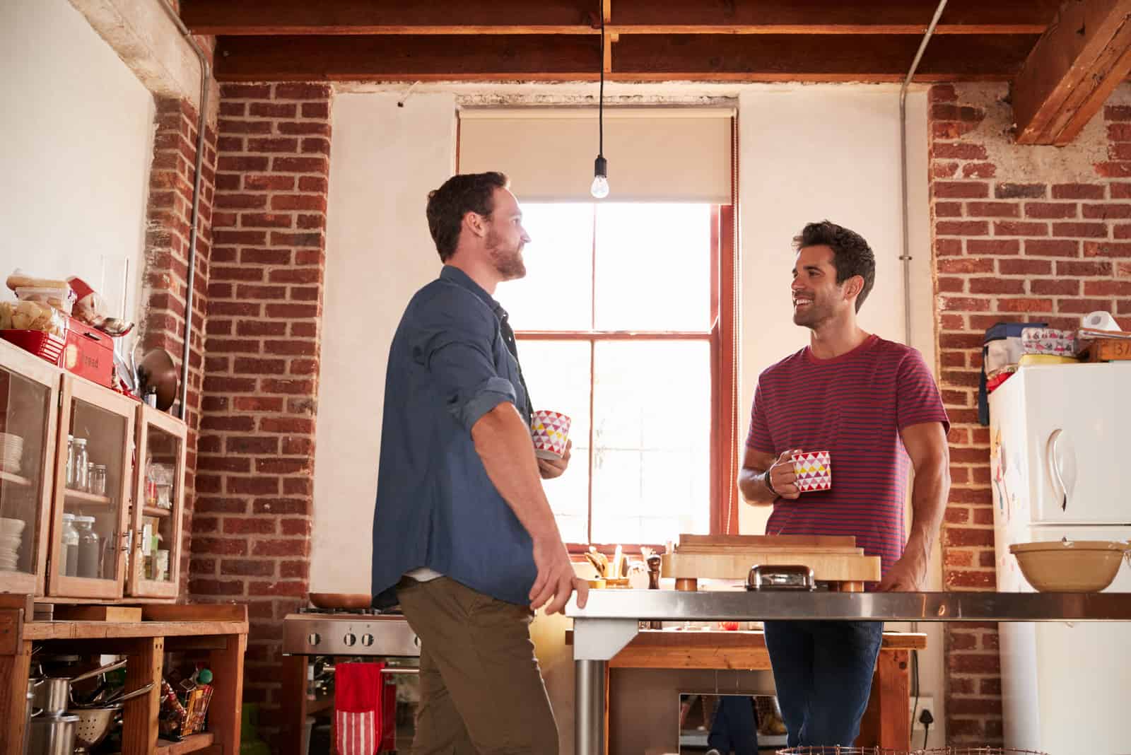 two male friends standing in kitchen drinking coffee