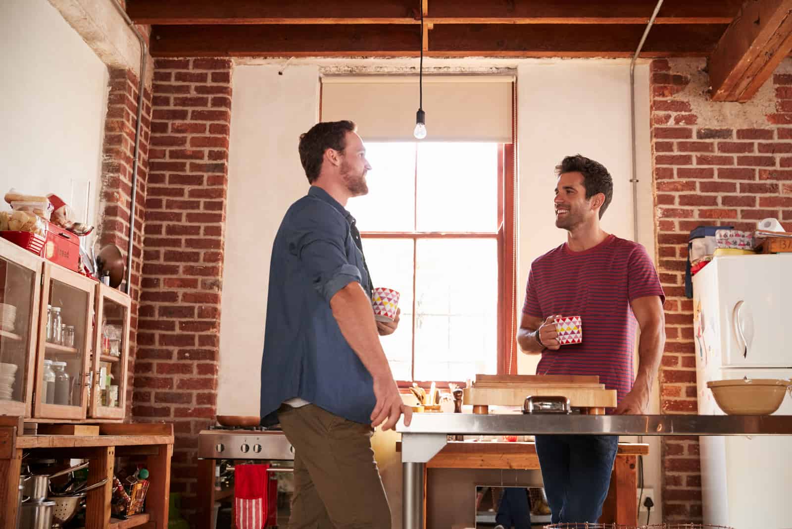 dos amigos de pie en la cocina tomando café