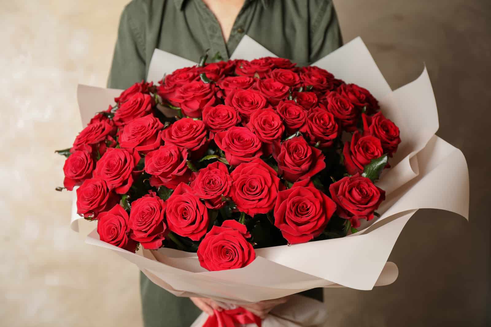 donna con in mano un grande bouquet di rose rosse