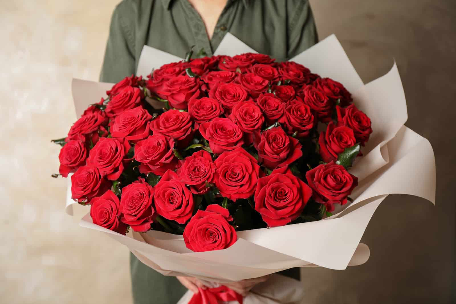 mujer sosteniendo gran ramo de rosas rojas