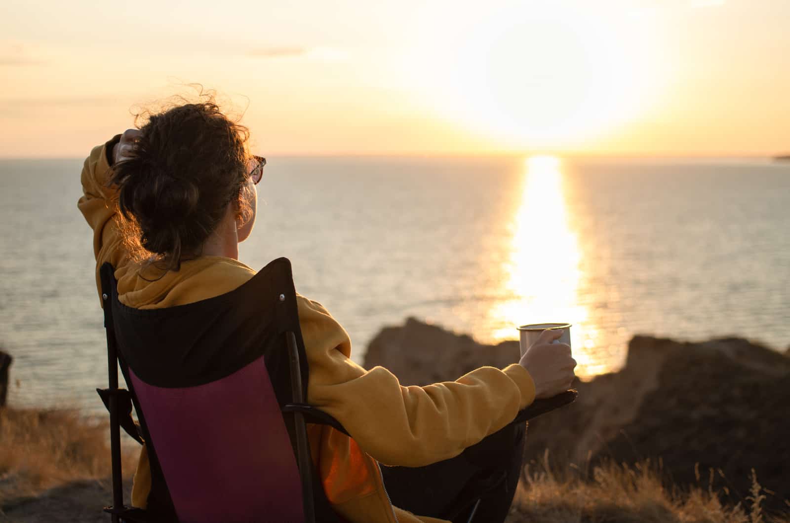 donna con tazza in mano che guarda il tramonto
