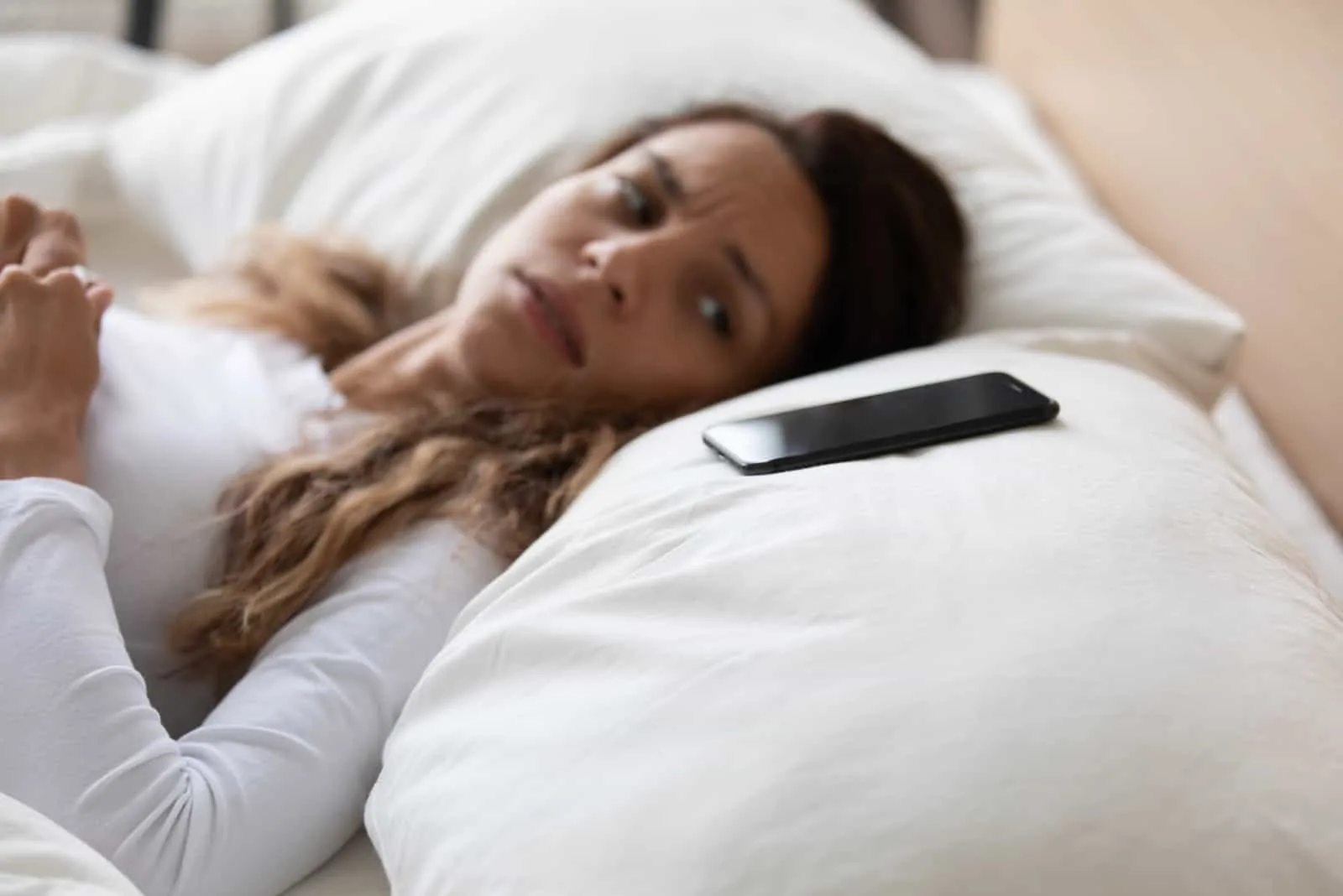 woman lying looking at her phone