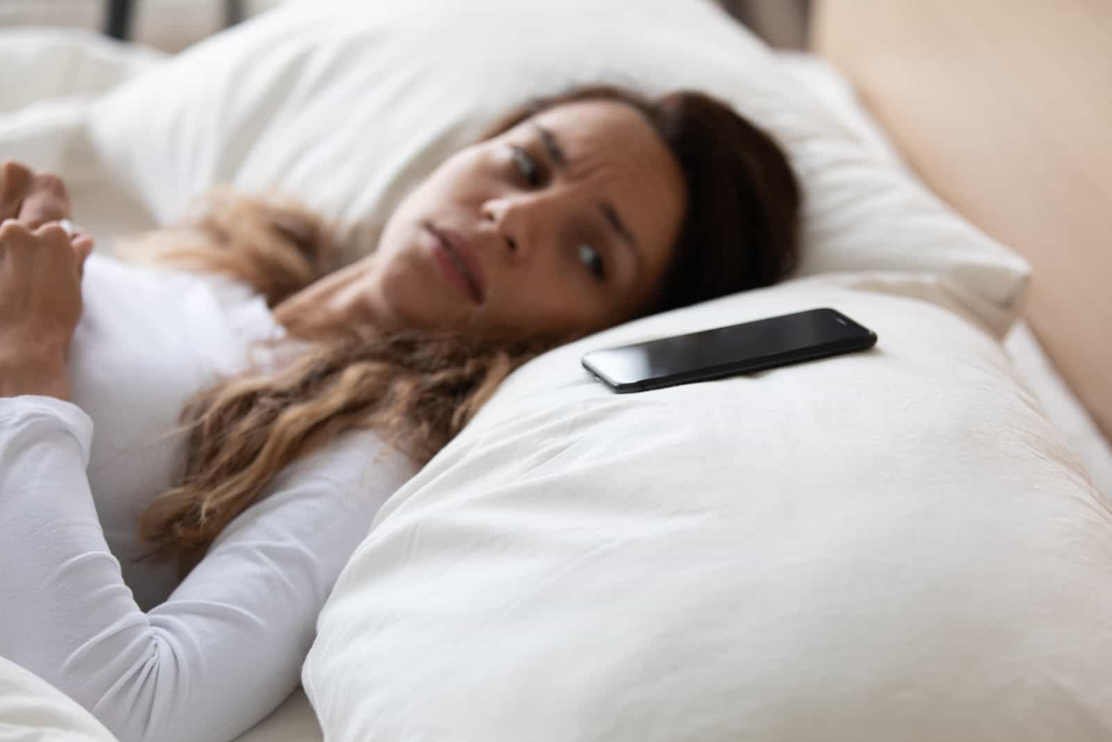 mujer tumbada mirando su teléfono