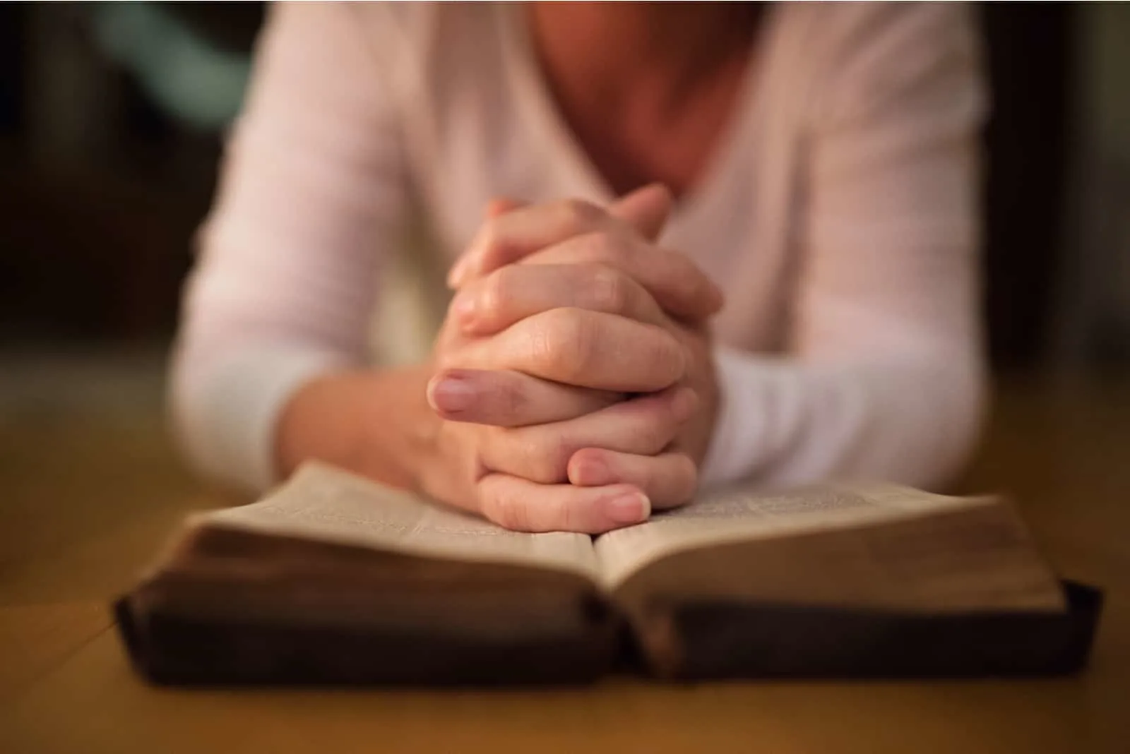 woman praying with hands on the Bible