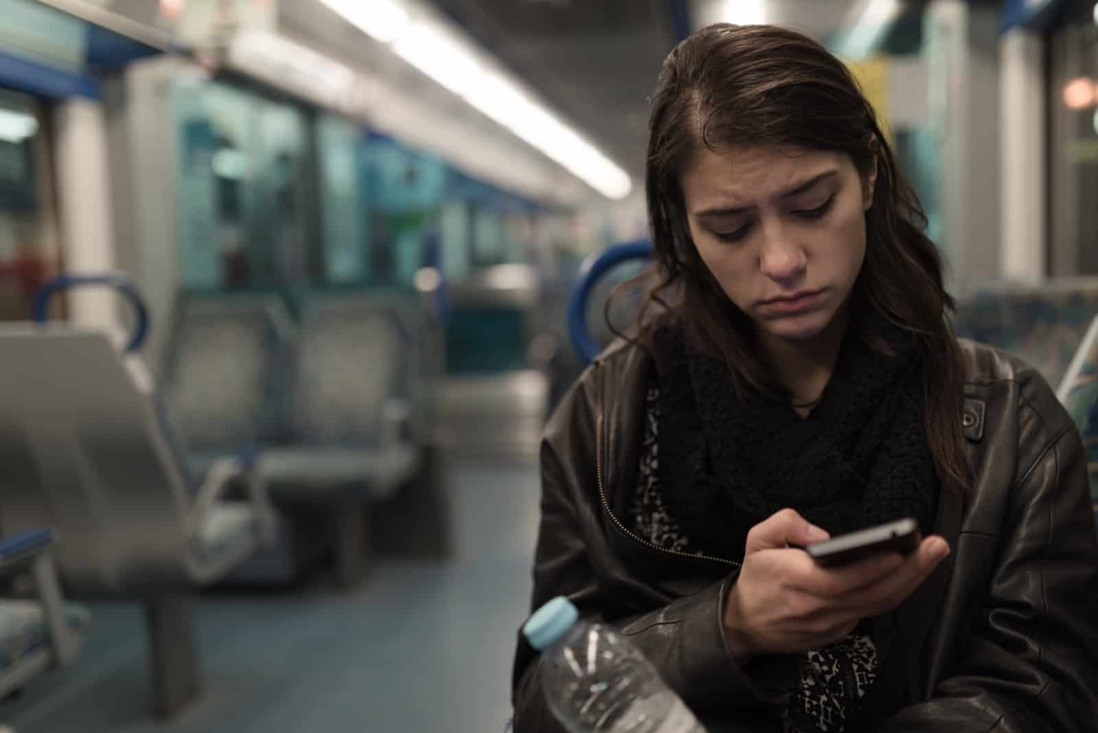 woman sitting in train looking at her phone