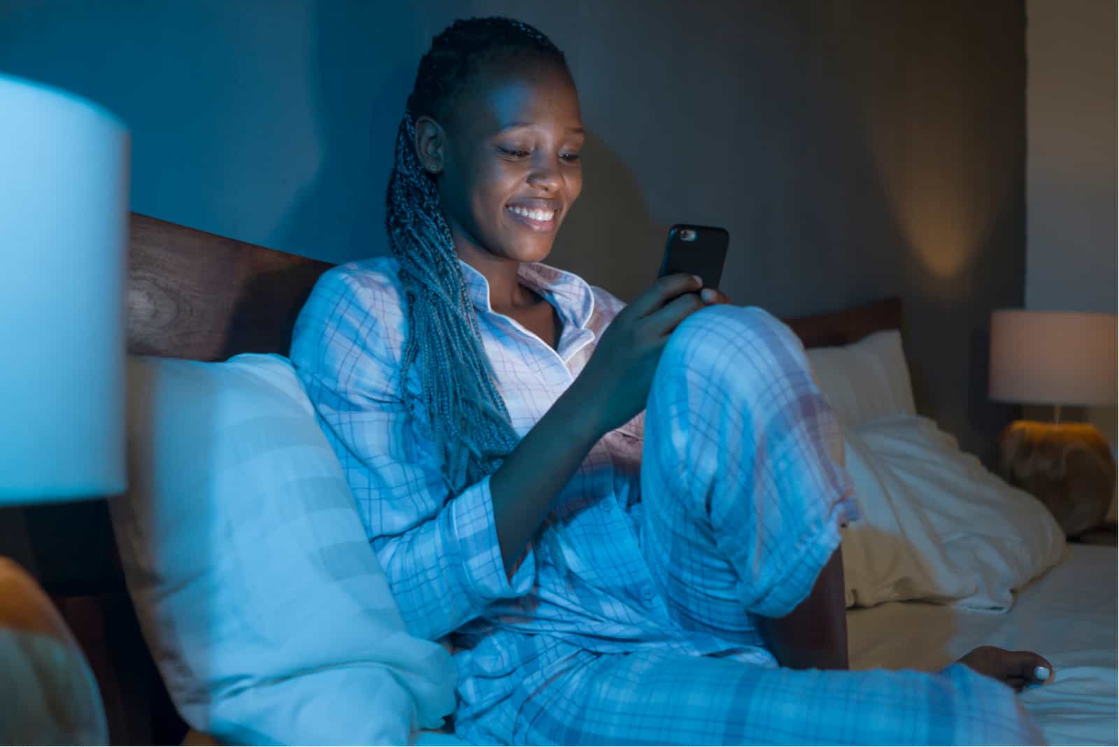 woman sitting on her bed wiht phone in hands