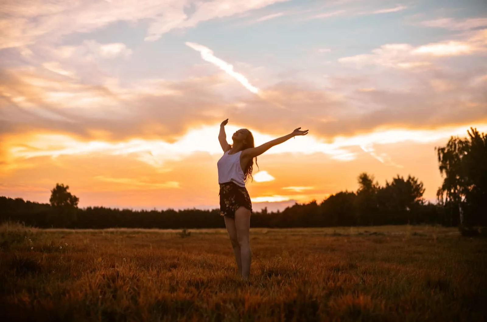 woman standing in field with arms up