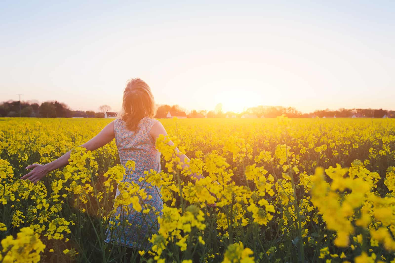 donna che cammina in un campo di fiori gialli